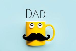 bonne fête des pères.tasse jaune avec moustache et yeux drôles levant les yeux avec le texte papa photo