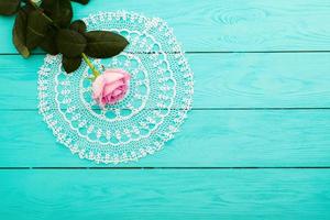 rose rose et serviette en dentelle sur fond en bois bleu. vue de dessus et espace de copie. fête des mères photo