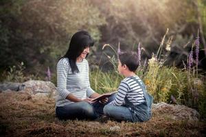 jeune femme lit un livre pour petit garçon photo
