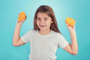 petite fille souriante tenant des oranges photo