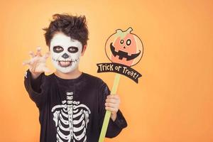 truc ou traiter.enfant drôle dans un costume de squelette avec citrouille d'halloween photo