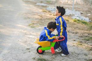 des enfants joyeux et souriants s'amusent sur le terrain avec une charrette à bras photo