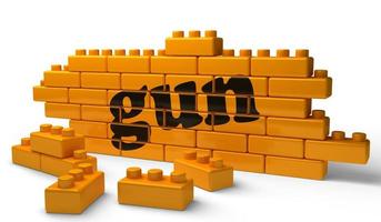 mot d'arme à feu sur le mur de briques jaunes photo