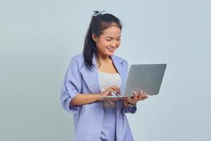 Portrait of smiling young asian woman looking at laptop isolé sur fond blanc photo