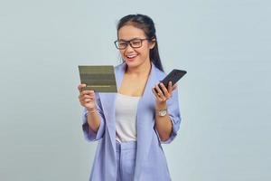 portrait d'une jeune femme asiatique joyeuse tenant un téléphone portable et regardant un livre de véhicule isolé sur fond blanc photo