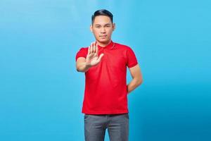 portrait d'un jeune homme asiatique agacé qui croise les mains fait un geste d'arrêt, démontre un rejet isolé sur fond bleu photo