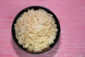 riz brun dans un bol noir sur une table rose photo