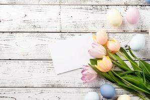 fond de pâques avec des oeufs et des tulipes sur fond de bois blanc, vue de dessus à plat photo