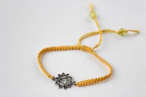 Bracelet tressé jaune avec chakra manipura sur fond blanc photo