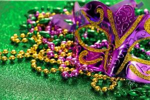 masque de carnaval et perles colorées sur fond vert brillant. notion de mardi gras.