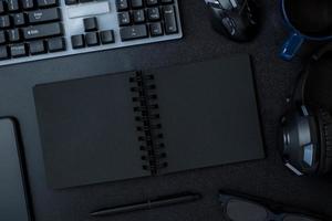 vue de dessus bureau de travail avec casque à clavier et cahier ouvert sur fond de tableau noir photo