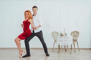 belle jeune femme vêtue d'une robe rouge et un homme qui danse, isolé sur fond blanc. photo