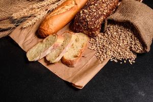 beau pain frais cuit au four avec des grains de blé sur un fond de béton foncé photo