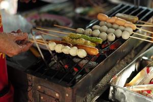 gros plan divers types de boules et de saucisses grillées au charbon de bois. l'alimentation de rue photo