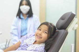 une petite fille mignonne ayant des dents examinées par un dentiste dans une clinique dentaire, un contrôle des dents et un concept de dents saines photo