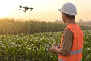 ingénieur masculin contrôlant la pulvérisation d'engrais et de pesticides par drone sur les terres agricoles, les innovations de haute technologie et l'agriculture intelligente photo