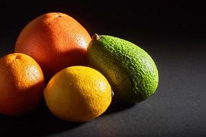 délicieuse orange fraîche, pamplemousse, avocat, citron isolé sur fond noir. photo