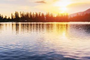 coucher de soleil sur le lac. lac de montagne majestueux dans le parc national des hautes tatras. strbske pleso, slovaquie photo