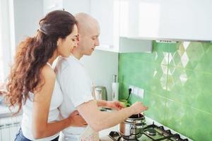 heureux jeune couple se préparant sur la cuisinière photo