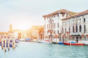 canal d'eau verte avec gondoles et façades colorées de vieux bâtiments médiévaux au soleil à venise, italie. photo