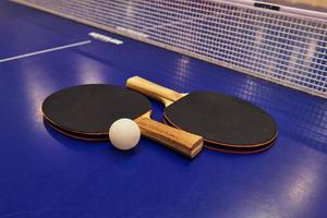 Raquette de tennis de table avec une balle sur une table bleue photo