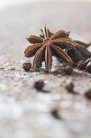 épices et herbes. ingrédients alimentaires et culinaires. étoiles d'anis et grains de poivre noir sur fond texturé photo