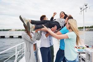 groupe d'amis heureux à la plage, homme jetant une femme heureuse. photo