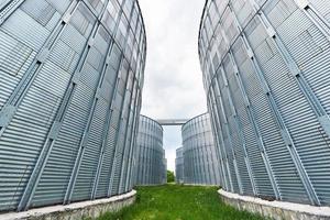 silos agricoles. extérieur du bâtiment. stockage et séchage des céréales, blé, maïs, soja, tournesol contre le ciel bleu avec des nuages blancs photo