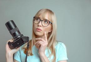 photographe de femme blonde élégante et joyeuse dans des verres et tenant un appareil photo. passe-temps, travail, concept de tir photo