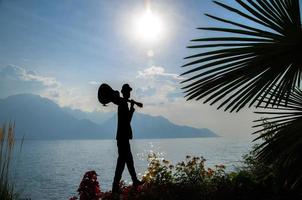 montreux, suisse - 14 septembre 2017 figure silhouette d'homme avec guitare et fleurs sur la promenade du lac léman lac léman en face des montagnes alpes, riviera suisse, canton de vaud photo