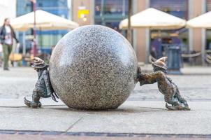 wroclaw, pologne, 7 mai 2019 deux nains poussent une boule de marbre, célèbre gnome miniature en bronze photo