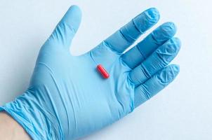 la main du travailleur médical dans des gants médicaux tenant une pilule photo