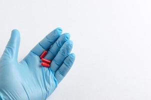 la main du travailleur médical dans des gants médicaux tenant une pilule photo