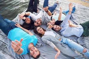 un groupe d'amis jeunes et prospères en vacances profitant d'un jeu sur le lac. Émotions positives. photo