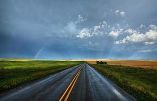 arc-en-ciel et route de campagne humide en saskatchewan photo