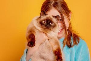 l'enfant sourit avec l'animal. une adolescente avec un chat pointu. photo