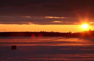 cabane de pêche sur glace sur un lac gelé au coucher du soleil photo