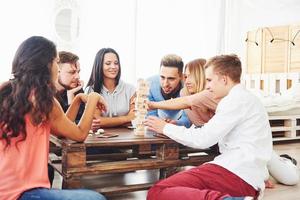 groupe d'amis créatifs assis à une table en bois. les gens s'amusent en jouant à un jeu de société photo