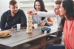 groupe d'amis créatifs assis à une table en bois. les gens s'amusent en jouant à un jeu de société photo