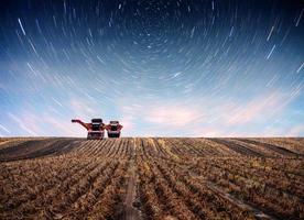 tracteur labourant le champ agricole en vue de la plantation de printemps. fantastique ciel étoilé et la voie lactée photo