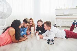 groupe d'amis créatifs assis à une table en bois. les gens s'amusent en jouant à un jeu de société photo