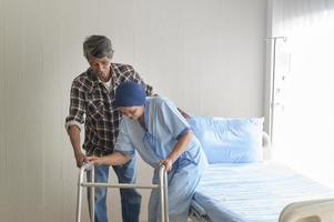 homme âgé aidant une femme patiente atteinte d'un cancer portant un foulard avec une marchette à l'hôpital, des soins de santé et un concept médical photo