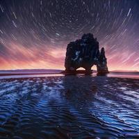 ciel étoilé dans un rocher spectaculaire dans la mer sur la côte nord de l'islande. les légendes disent que c'est un troll pétrifié photo