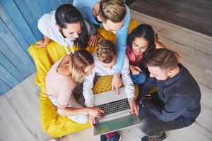 groupe de jeunes amis créatifs suspendus au concept de médias sociaux. les gens discutent ensemble d'un projet créatif pendant le processus de travail, jouent à des jeux ou regardent un film vidéo photo