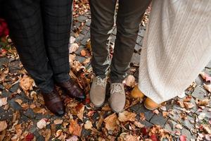 pieds des mariés, ainsi que de leur fils sur fond de feuilles d'automne photo