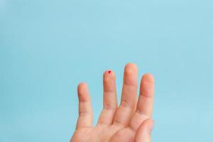 goutte de sang sur le doigt d'un enfant. le concept de mesure de la glycémie à l'aide de bandelettes. fond bleu photo