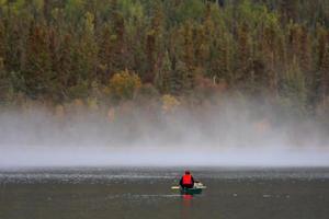homme en canoë près de la brume matinale sur le lac photo