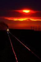 vue panoramique d'un train qui approche près du coucher du soleil photo