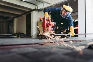 l'artisan soudeur coupe le travail de l'acier dans l'atelier de fabrication, le soudeur dans les équipements de protection de sécurité fait le travail du métal sur le chantier de construction. compétence de la main-d'œuvre en acier et concept de production d'ateliers photo