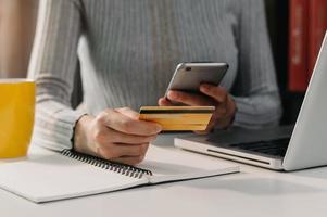 femme utilisant un smartphone pour les achats en ligne de paiements mobiles,canal omni,assis sur une table,écran d'interface graphique d'icônes virtuelles photo